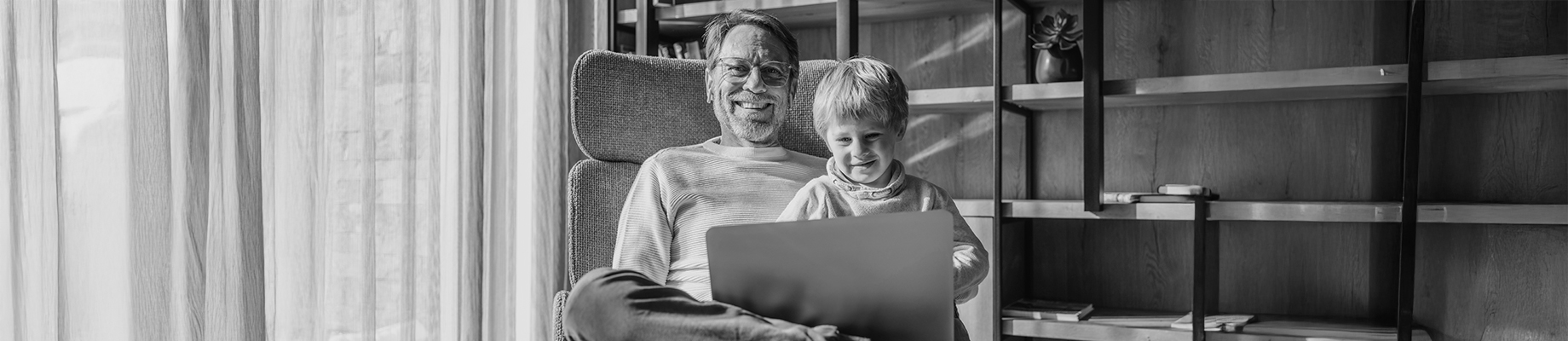 Bild. Großvater sitzt mit Enkel vor Laptop